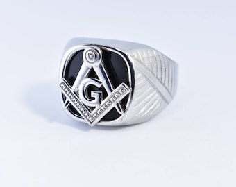 May include: A silver ring with a black onyx stone featuring a silver Masonic symbol.