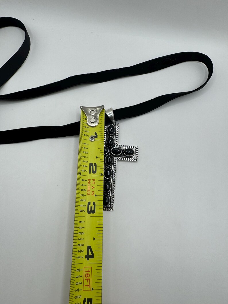 Op de afbeelding: Een zilveren kruis hanger met zwarte accenten en een zwart fluwelen lint van 7,6 cm lang.