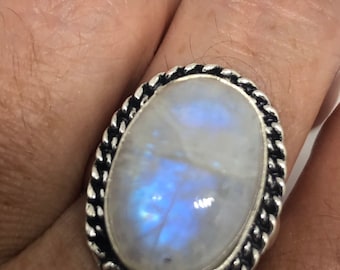 Puede incluir: Un anillo de plata con una gran piedra de luna ovalada engastada en una banda trenzada.