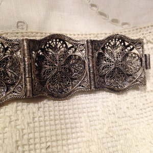 Puede incluir: Un brazalete de filigrana de plata con un delicado dise&ntilde;o floral. El brazalete est&aacute; hecho de varias secciones que est&aacute;n unidas por bisagras.