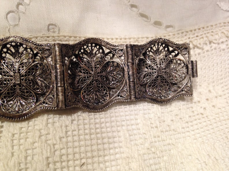 Puede incluir: Un brazalete de filigrana de plata con un delicado dise&ntilde;o floral. El brazalete est&aacute; hecho de varias secciones que est&aacute;n unidas por bisagras.