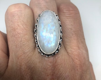 Puede incluir: Un anillo de plata con una gran piedra de luna ovalada engastada en una banda de plata retorcida.