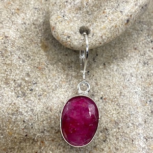 May include: Silver dangle earrings with a bright red oval gemstone.