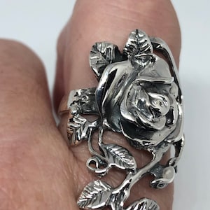 May include: A silver ring featuring a detailed rose design with leaves and stems. The rose is the focal point of the ring, with intricate details in the petals and leaves.