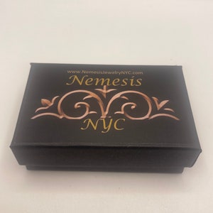 May include: Black jewelry box with gold lettering that reads "www.NemesisjewelryNYC.com Nemesis NYC".