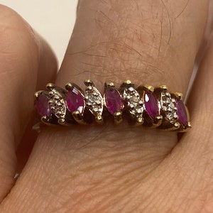 May include: A gold ring with a row of marquise-shaped ruby stones and smaller diamond accents.