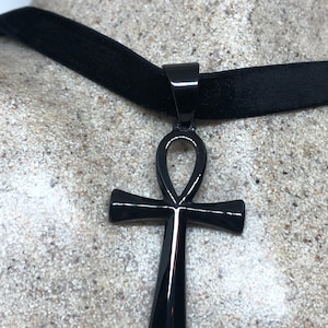 May include: A black velvet choker necklace with a black metal ankh pendant.