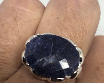 May include: A silver ring with a large, oval-shaped, dark blue gemstone.