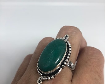 May include: A silver ring with a large oval green gemstone set in a decorative silver setting.