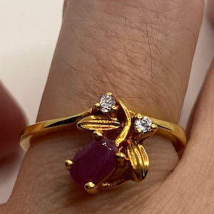 May include: A gold ring with a ruby and two small diamonds set in a floral design.