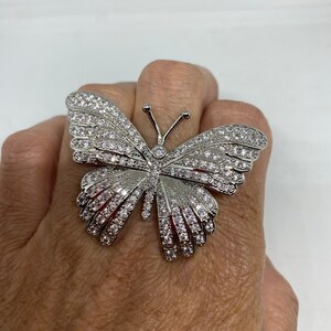 K&ouml;nnte beinhalten: Ein silberner Schmetterlingsring mit klaren Strasssteinen. Der Ring ist gro&szlig; und hat ein detailliertes Design.