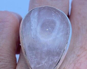 May include: A teardrop-shaped ring with a clear, cloudy, white gemstone set in a silver band.