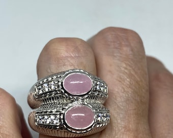 May include: A silver ring with two pink oval stones and clear round stones set in the band.