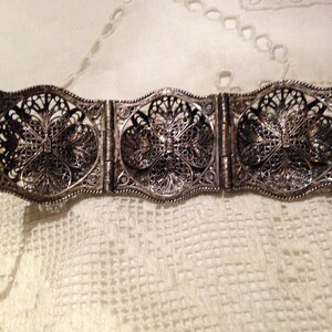 Puede incluir: Un brazalete de filigrana de plata con un delicado dise&ntilde;o floral. El brazalete est&aacute; hecho de varias secciones que est&aacute;n conectadas por bisagras.