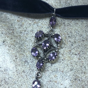 May include: A black velvet choker necklace with a silver pendant featuring a cluster of purple amethyst stones.