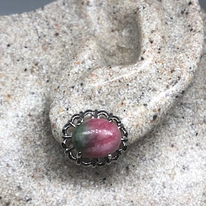 Puede incluir: Un par de pendientes de plata con una piedra ovalada rosa y verde engastada en un marco de plata decorativo.
