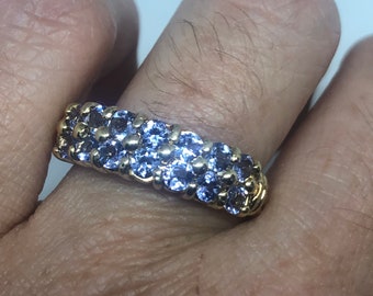 May include: A gold band ring with a row of small, purple gemstones.