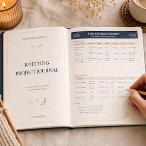 May include: An open knitting project journal by Bright Bridge Paper Co. with a left page titled Knitting Project Journal and a right page featuring a Yarn and Needle Inventory table with handwritten entries and a gold pen resting on the page.