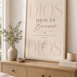Könnte beinhalten: Ein gerahmter Wandkunstdruck mit dem spanischen Text DIOS, DIOS ES Bueno, TODO EL TIEMPO, Y TODO EL TIEMPO DIOS ES BUENO, NAHUM 1:7 in Braun- und Beigetönen. Das Design enthält ein kleines Herzsymbol und eine Strichzeichnung eines Blattzweigs.