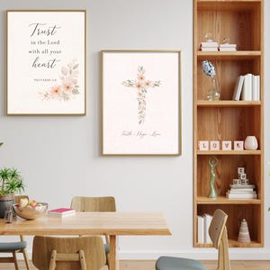 Puede incluir: Dos impresiones artísticas enmarcadas con marcos dorados. Una presenta el texto "Trust in the Lord with all your heart" y detalles florales. La otra muestra un diseño de cruz floral con el texto "Faith, Hope, Love".