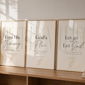 Puede incluir: Tres láminas rectangulares de pared en marcos dorados finos con fondos beige y texto en negro. Las láminas muestran citas religiosas como Trust His Timing, God's Plan y Let go and Let God, cada una con una pequeña ilustración de una hoja.