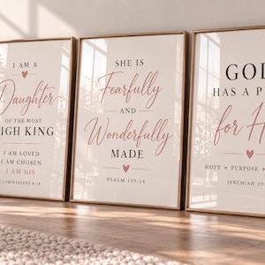 Puede incluir: Tres láminas de pared enmarcadas con fondo crema, texto negro con serifa y letras rojas en cursiva. La primera lámina dice I AM A DAUGHTER OF THE MOST HIGH KING, la segunda SHE IS FEARFULLY AND WONDERFULLY MADE y la tercera GOD HAS A PLAN for Her.