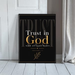 Puede incluir: Impresión enmarcada en negro con texto dorado y blanco que dice "Confía en Dios con todo tu corazón" y "Proverbios 3:5". La palabra "TRUST" está en una fuente descolorida en la parte superior. Un borde dorado rodea la impresión.