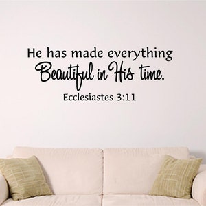 May include: A white wall with black text that reads "He has made everything beautiful in His time. Ecclesiastes 3:11". A white couch with two pillows is in the foreground.