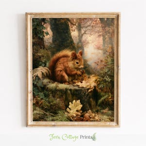 May include: A framed art print featuring a detailed painting of a reddish-brown squirrel sitting on a mossy tree stump in a forest. The squirrel holds a nut amidst fallen autumn leaves, ferns, and ivy, with soft light filtering through the trees.