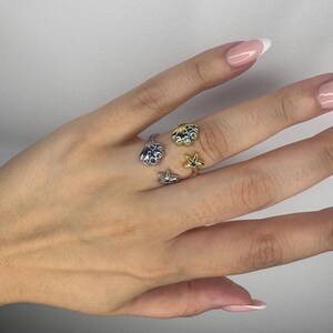 May include: Two open-style rings featuring nautical motifs. One ring is silver-toned with a seashell and a small starfish. The other ring is gold-toned with a seashell accented by light blue stones and a small starfish with a dark centre stone.