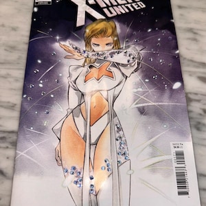 Puede incluir: Portada del cómic X-Men United #1. Presenta a un personaje femenino con un atuendo blanco y naranja con detalles brillantes. El fondo es morado y blanco. Se ve el logo de Marvel.