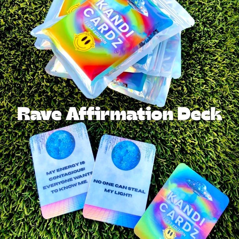 May include: A stack of Kandi Cardz First Edition affirmation decks in clear plastic pouches and three individual cards featuring a blue moon graphic, a grid pattern, and the text My energy is contagious! Everyone wants to know me and No one can steal my light!