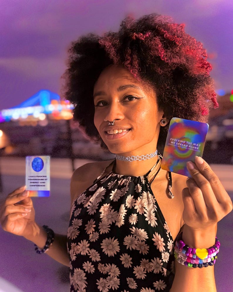 May include: Two rectangular cards with holographic finishes. The left card features a blue circular graphic and text. The right card displays a colorful swirl pattern with the text "EVOLVING THE WAY WE SPREAD PLUR" printed in white.