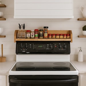 May include: A black and white electric stove with a wooden spice rack holding various spice jars. Two glass bottles with black tops sit to the left of the spices. The stove has four burners and a digital display.