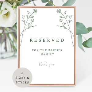 May include: A framed sign with a white background and the words "RESERVED FOR THE BRIDE'S FAMILY" in dark green. The sign is decorated with green floral line art and the words "thank you" in a script font. A circular graphic at the bottom says "2 SIZES & STYLES".