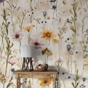 Puede incluir: Una mesa de madera con una l&aacute;mpara peque&ntilde;a y un cuenco con objetos decorativos se encuentra frente a un papel pintado floral. La l&aacute;mpara tiene una pantalla con un patr&oacute;n de chevron gris y blanco. El papel pintado presenta flores de acuarela en tonos amarillos, rosas y morados.