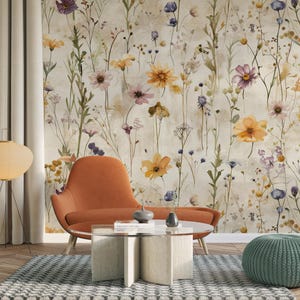 Puede incluir: Un sill&oacute;n naranja y una mesa de centro con tapa de cristal y base beige est&aacute;n frente a un papel pintado floral. Un puf verde y una l&aacute;mpara de pie con pantalla redonda de papel tambi&eacute;n est&aacute;n en la habitaci&oacute;n. El papel pintado presenta flores coloridas.