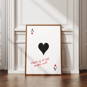 Puede incluir: Una impresión enmarcada del As de Corazones de una baraja. La carta presenta un gran corazón negro, la letra "A" con un pequeño corazón rojo y el texto "What if it all works out?" en rojo. El marco es marrón.