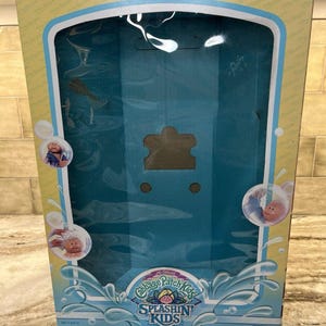 May include: Vintage Cabbage Patch Kids Splashin' Kids box. The box is yellow and blue with the text "I Can Take a Bath With You!". The box has a clear plastic window and features images of the dolls in bubbles.
