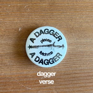 May include: A round, light blue button with the words "A DAGGER" in a circular pattern, with "please" and "fetch me" in the center, and a dagger illustration. The text "dagger verse" is below the button.