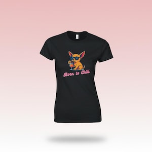 Könnte beinhalten: Schwarzes T-Shirt mit einem Cartoon-Chihuahua, der eine Sonnenbrille trägt und einen Cocktail hält. Der Text "Born to Chill" steht in rosa Schrift darunter. Das Shirt hat einen Rundhalsausschnitt.