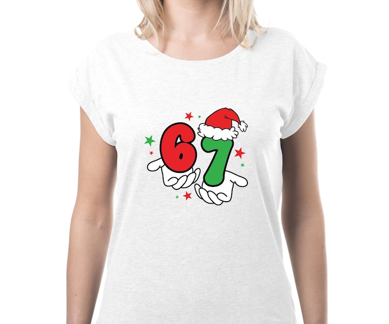 May include: White t-shirt with a festive graphic. The design features the numbers "6" and "7" in red and green, respectively, held by cartoon hands. The number "7" is wearing a Santa hat, with red and green stars.