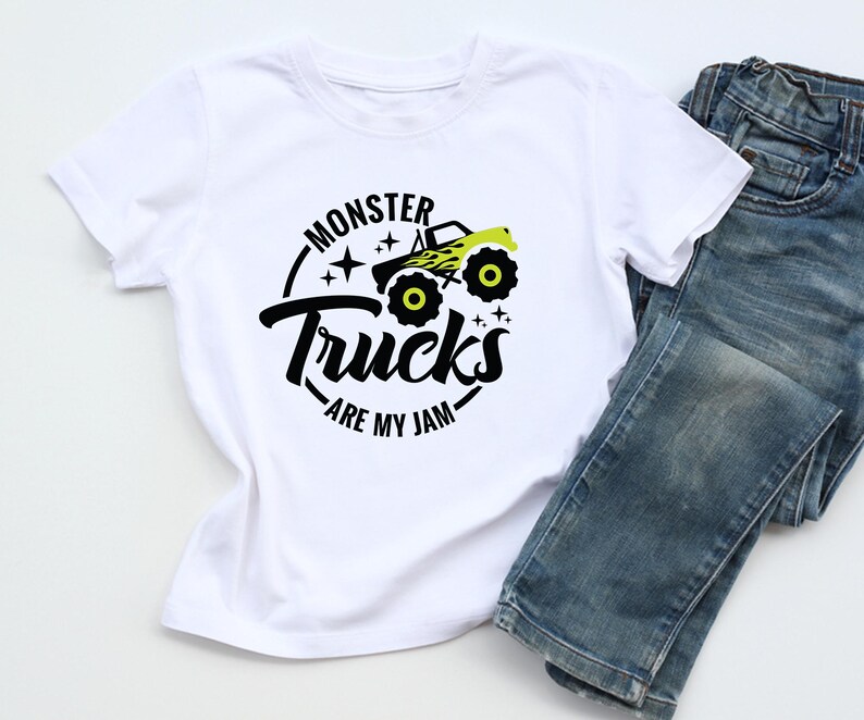 May include: White t-shirt with a black and neon green graphic of a monster truck and the text "Monster Trucks are my Jam." The shirt is paired with blue denim jeans.