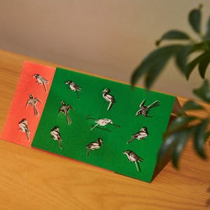 Op de afbeelding: Tweeledige briefpapierset met vogelillustraties. Eén deel is rood, het andere is groen. Het groene deel heeft de tekst "Good morning" in cursief. De vogels zijn zwart-wit met grijstinten.