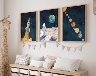 以下が含まれることがあります： 宇宙をテーマにした3つの額入り水彩画。1つは打ち上げられるロケット、もう1つは月面に着陸した宇宙飛行士と地球、3つ目は太陽系の惑星を描いています。プリントは収納ベンチの上に飾られています。