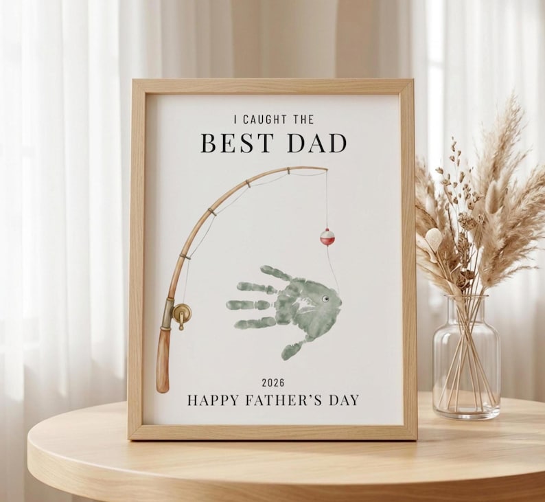 May include: A framed print with the text "I CAUGHT THE BEST DAD" above a watercolor illustration of a fishing rod and a handprint fish. The words "HAPPY FATHER'S DAY" are below the illustration.