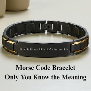 Pode incluir: Uma pulseira de elos em preto fosco com detalhes em tom dourado nas bordas e uma placa retangular central gravada com símbolos de código Morse. A pulseira inclui um fecho de metal seguro e é exibida com o texto Morse Code Bracelet Only You Know the Meaning.
