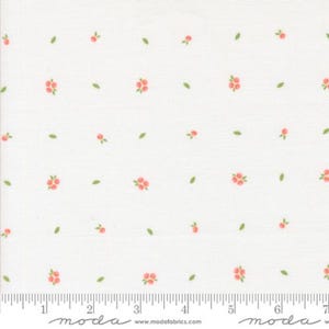 May include: White fabric with a repeating pattern of small pink flowers and green leaves. The fabric is measured with a ruler in inches.