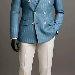 Puede incluir: Un blazer azul claro de doble botonadura con rayas blancas, combinado con pantalones blancos. El blazer tiene botones blancos y un pañuelo de bolsillo blanco. El texto "HUSSAINBYANAS" es visible en la parte superior.