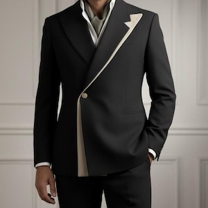 Może przedstawiać: Czarny garnitur z kremowym akcentem na klapie i zapięciem na jeden guzik. Garnitur jest połączony z czarnymi spodniami i białą koszulą z kołnierzykiem. Jasnozielony szalik jest noszony wokół szyi. Tekst "HussainbyAnas" znajduje się na dole.